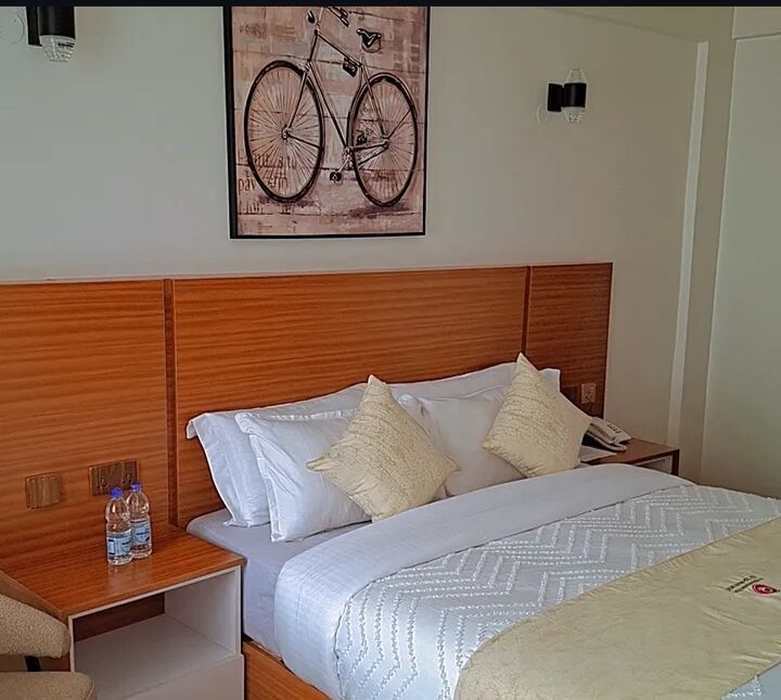 Bed with warm timber headboard and white linen at Crown Boutique Hotel